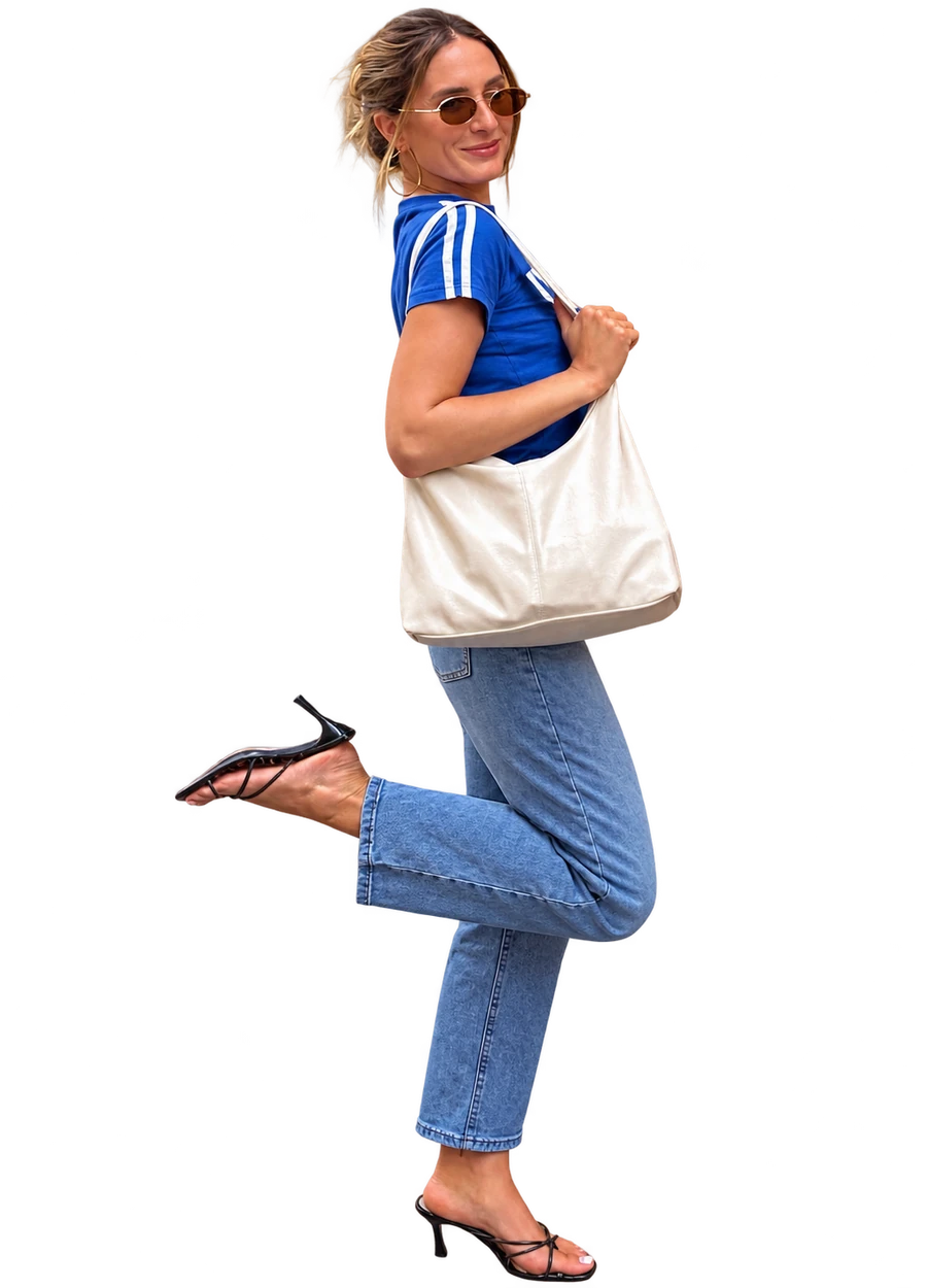 Bella Tomelleri in a blue tee, jeans and heels, carrying a cream shoulder bag