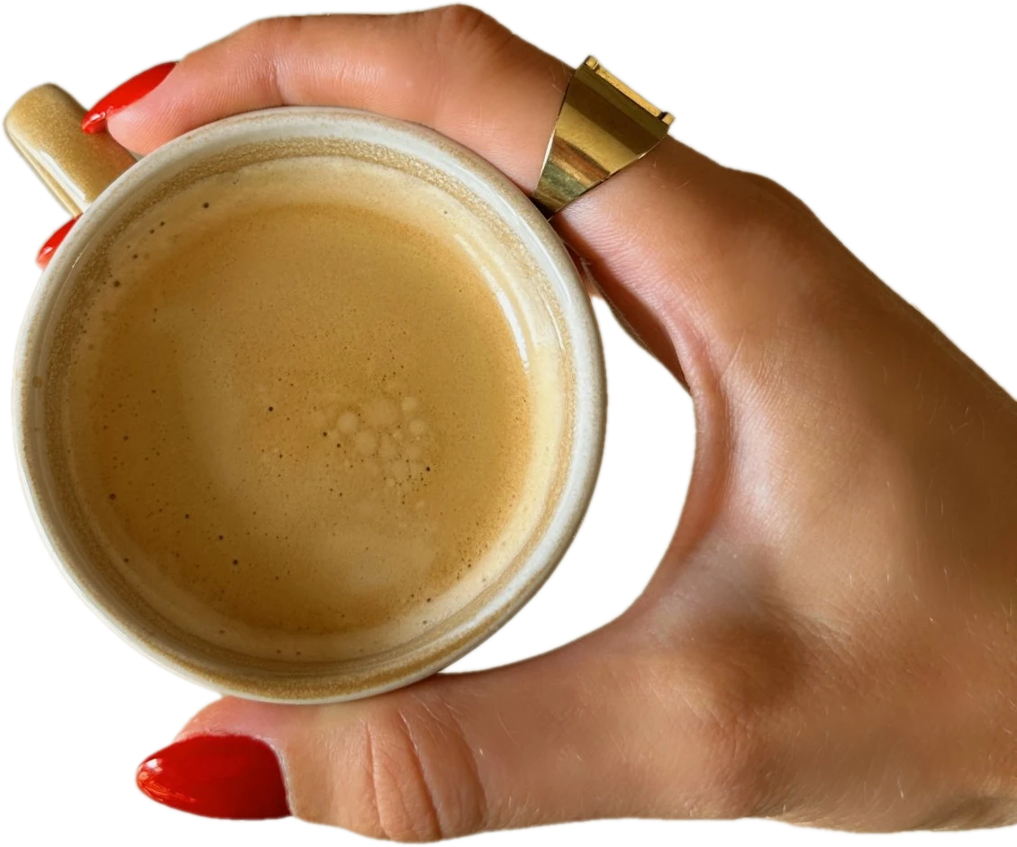 Bella's hand with red nails and a gold ring holding a cup of coffee